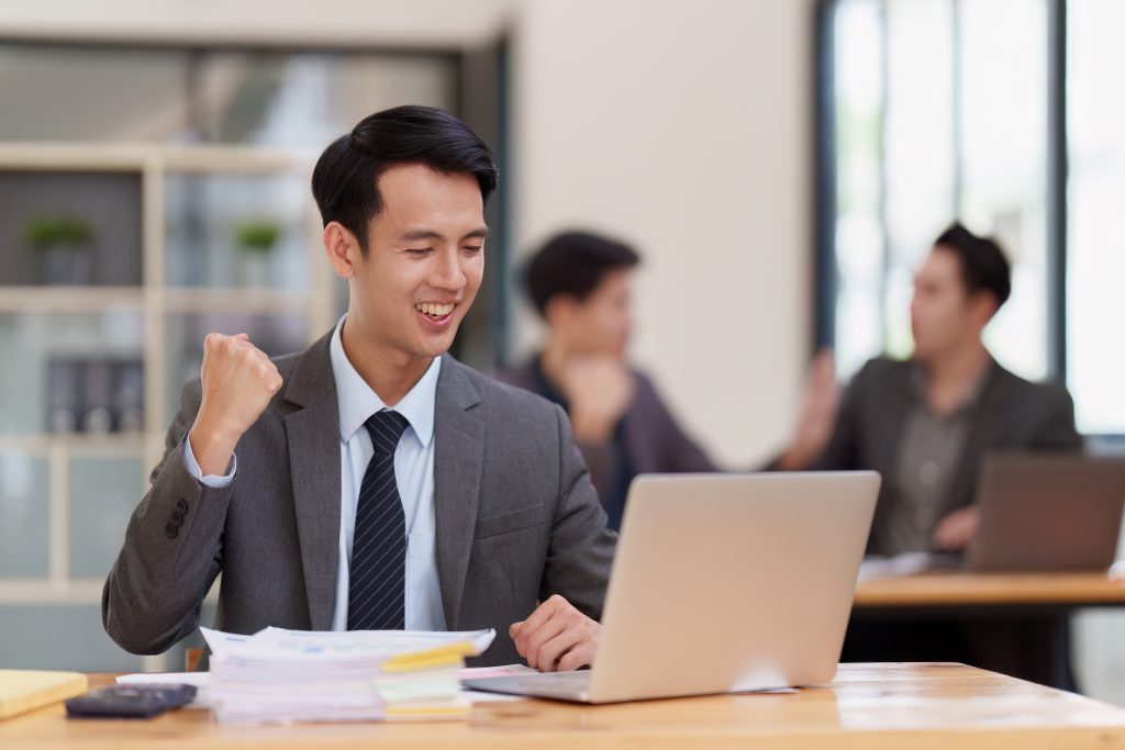 Asian Businessperson using laptop and celebrating victory and success, have good news, job celebrating achievement..