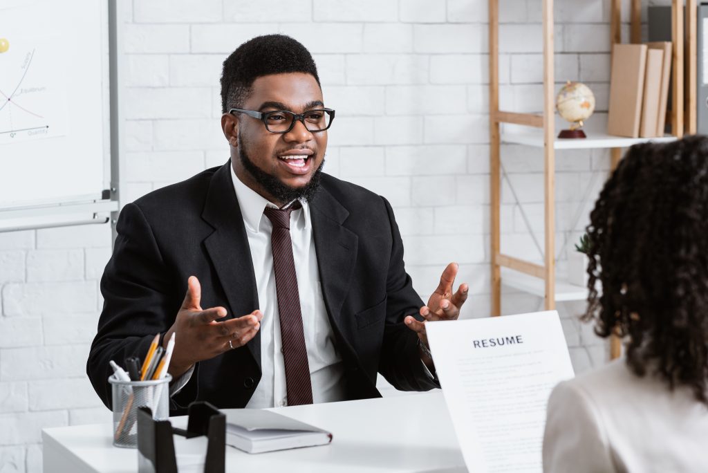 Human resources manager communicating with positive vacancy applicant on employment interview at office. HR specialist talking to job candidate, looking through CV
